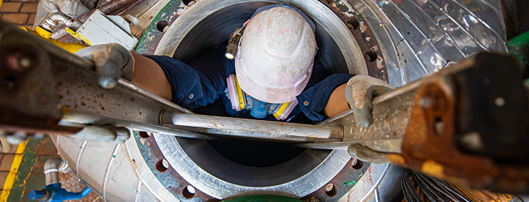 Entry supervisor authorizing a confined space permit beside an open tank hatch